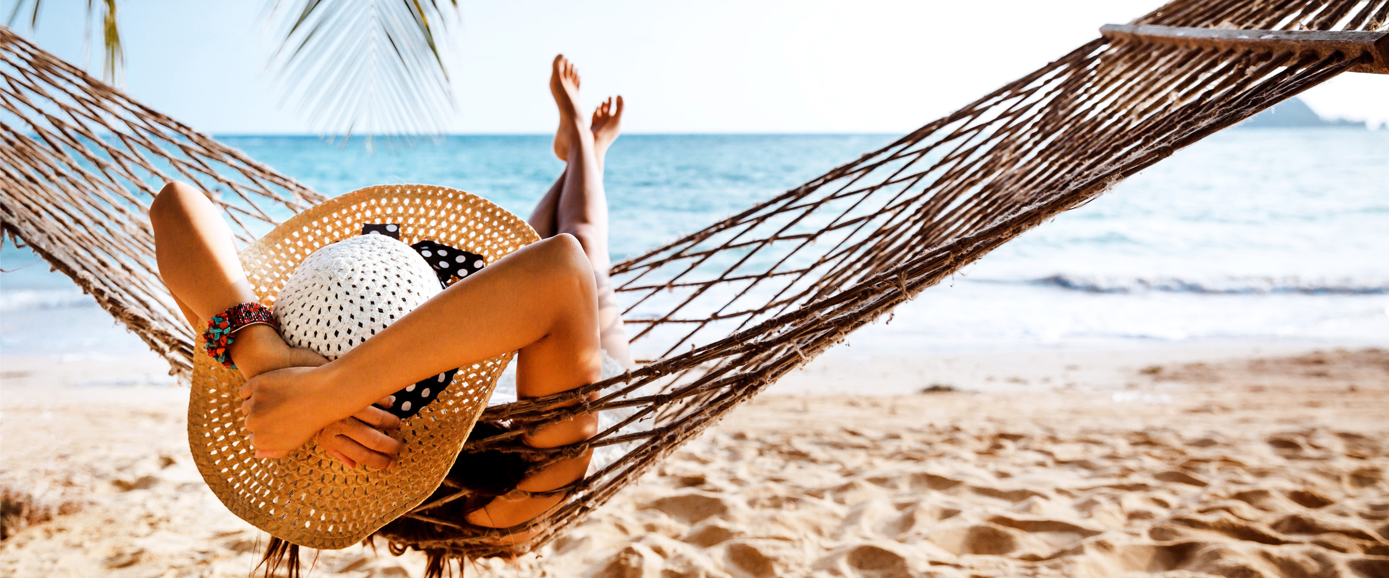 Photo of a woman lying in a hammock on the beach.